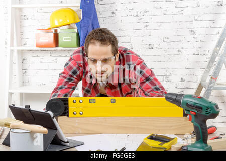 a  young man viewing a spirit level,  to read the position of the bubble to ensure a horizontal line Stock Photo