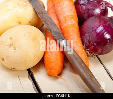 basic vegetable ingredients carrot potato onion on a rustic wood table Stock Photo