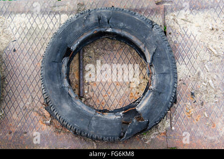 Completely torn tyre abandoned on a rusty metal plate Stock Photo