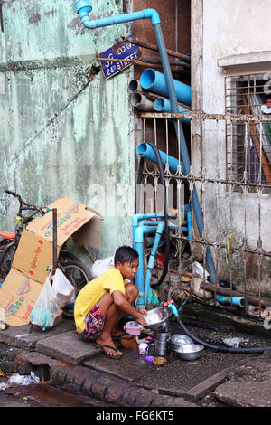 Boy washing dishes in the street, Yangon, Myanmar Stock Photo