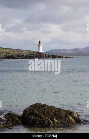 Lighthouse at the water's edge under a cloudy sky; Port Charlotte, Isle ...