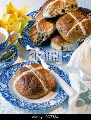 Hot cross buns on plate ith knife and cup of tea in studio setting Stock Photo