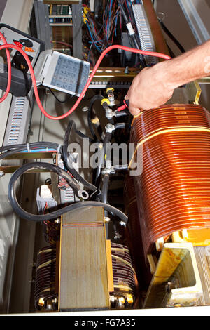 Engineer works in an electrical control cabinet in the plant Stock Photo