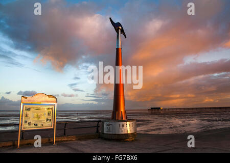 Rotating tall spinning weathervane Southport, Seafront & Promenade attractions. Colourful sunset over the Irish Sea on the north west coast of Sefton.  UK Weather wind vane, wind speed and direction instrument;   This device is a TPT Seamark on Southport’s Promenade, a  tall towering outdoor weather station wind spinner, which serves as a marker for the start of the east-west trail of The Trans Pennine coast-to-coast trail. Stock Photo