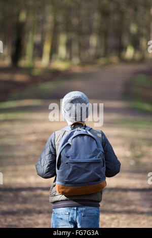 A boy with a rucksack walking in the woods Stock Photo