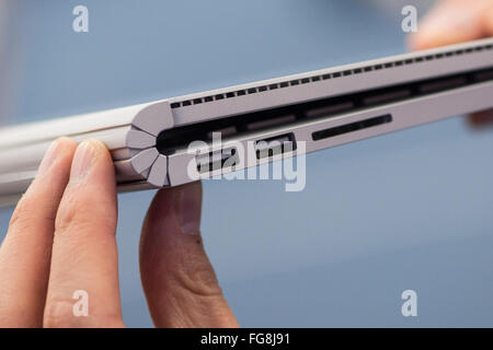 Hamburg, Germany. 18th Feb, 2016. ILLUSTRATION - A man holds up a Microsoft Surface Book to show the USB ports, SD card slot and the flip mechanism in an electronics store in Hamburg, Germany, 18 February 2016. The Surface Book has a touch screen that also allows it to be used as a tablet. Photo: LUKAS SCHULZE/dpa/Alamy Live News Stock Photo