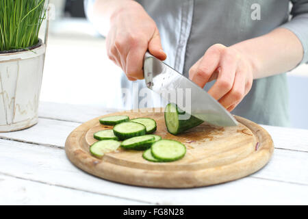 Hands woman standing in the kitchen while slicing cucumber. Green diet, a woman cut cucumbers. Green salad, light diet Stock Photo