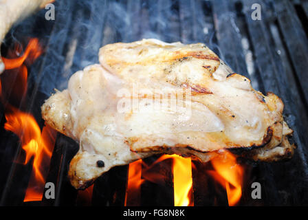 Raw Chicken Thigh on a Flaming Grill Stock Photo