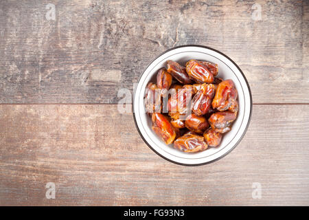 Dried dates in a bowl on wooden background. Stock Photo