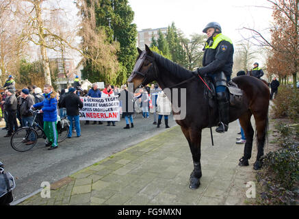 A policeman on a horseback is watching people who are demonstrating against a huge migrant camp for refugees Stock Photo