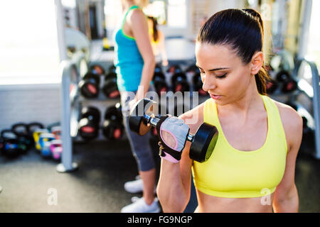 Two fit women in gym working out with weights Stock Photo