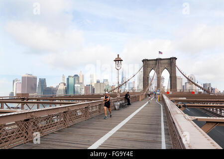 people engaged in bike run and others running on brooklyn bridge new york with manhattan in the background Stock Photo