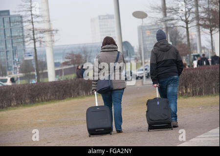 Berlin, Germany. 18th Feb, 2016. A woman and a man with suitcases walking through the government quarter in Berlin, Germany, 18 February 2016. After remarkable growths in the past years, Berlin again achieved top numbers in the tourism business in 2015. More than 30 million over-night stays of German and foreign visitors have been counted - more than ever. Photo: Paul Zinken/dpa/Alamy Live News Stock Photo