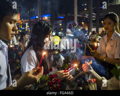 Feb. 18, 2016 - Bangkok, Bangkok, Thailand - College students light their incense before praying for love at the Trimurti Shrine in Bangkok. Every Thursday night, starting just after sunset and peaking at 21.30, hundreds of Bangkok single people, or couples seeking guidance and validation, come to the Trimurti Shrine at the northeast corner of Central World, a large Bangkok shopping mall, to pray to Lord Trimurti, who represents the trinity of Hindu gods - Brahma, Vishnu and Shiva. Worshippers normally bring an offering of red flowers, fruits, one red candle and nine incense sticks. It's belie Stock Photo