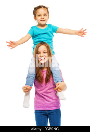 Happy young girl sitting on sister's shoulders Stock Photo