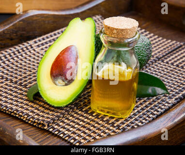 Avocado oil bottle with avocado fruit on wooden background Stock Photo