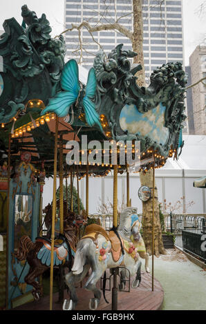 Carousel / Merry-go-round in Bryant Park with elaborate carving and horses, shot in winter as it is snowing. Stock Photo