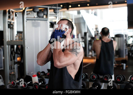 muscular man wiping sweat from his face in the gym Stock Photo