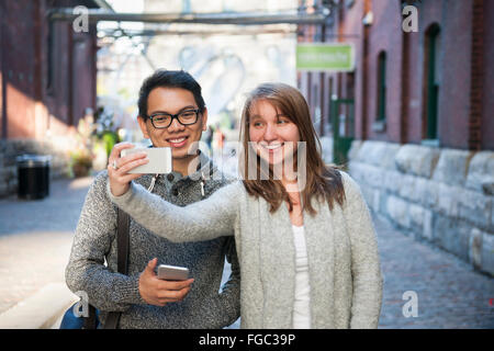 Two young people taking a selfie with smartphone on city street Stock Photo