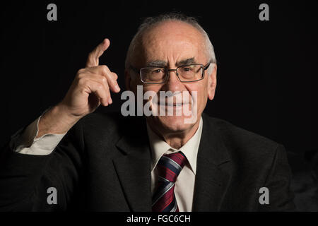 older businessman, wearing eyeglasses on black background pointing with his finger Stock Photo