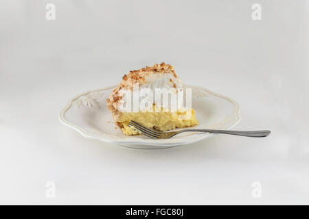 A slice of homemade freshly baked coconut cream meringue pie isolated on white. Stock Photo