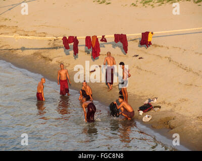Group of adult male Buddhist monks bathing and washing their clothes on the Irrawaddy river banks in central Myanmar (Burma). Stock Photo