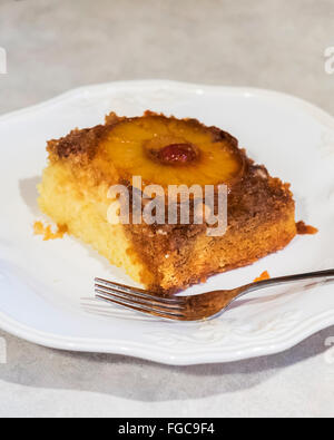 A serving of pineapple upside down cake on a plate, with brown sugar,pineapple slices, maraschino cherries and pecan topping. Oklahoma, USA. Stock Photo