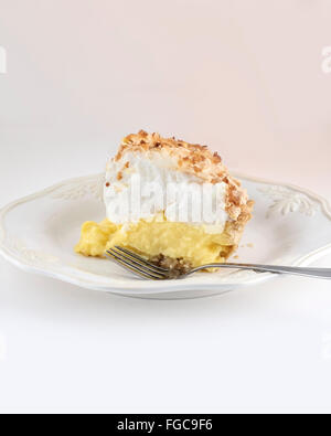 A slice of homemade freshly baked coconut meringue pie isolated on white.Color fade added. Stock Photo