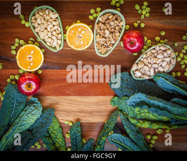 Fruits, nuts, kale leafs, and wasabi peas on wooden table. Top view. Stock Photo