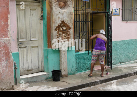 Woman cleaning sidewalk in front of home, Habana Vieja (Old Havana), Cuba Stock Photo