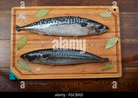 Two mackerels on wooden plate over brown wooden table with spices Stock Photo
