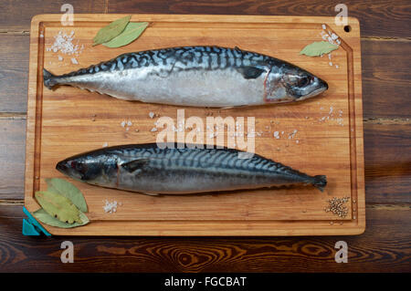 Two mackerels on wooden plate over brown wooden table with spices Stock Photo
