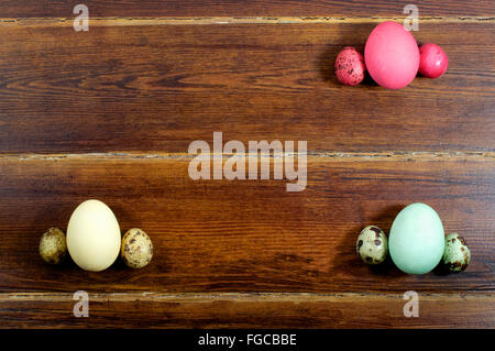 Various eggs and quail eggs with card over wooden background from top
