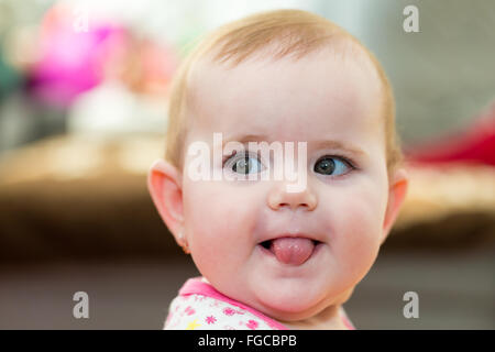 Happy cute little one year old girl indoor smiling and stick your tongue Stock Photo