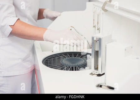 Lab tech loading samples into a chemistry analyzer Stock Photo