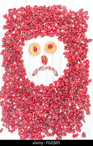 Sad face made of dried fruits on white wooden background. Stock Photo
