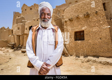 Portrait of an old Berber man with traditional costumes in front of the old ruins of the city of Siwa. Stock Photo