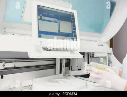 Lab tech loading samples into a chemistry analyzer Stock Photo
