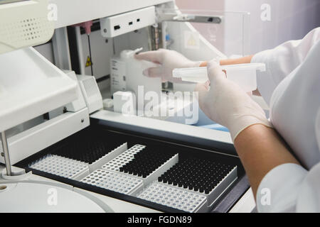 Lab tech loading samples into a chemistry analyzer Stock Photo