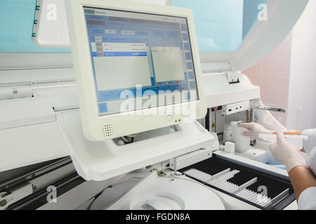 Lab tech loading samples into a chemistry analyzer Stock Photo