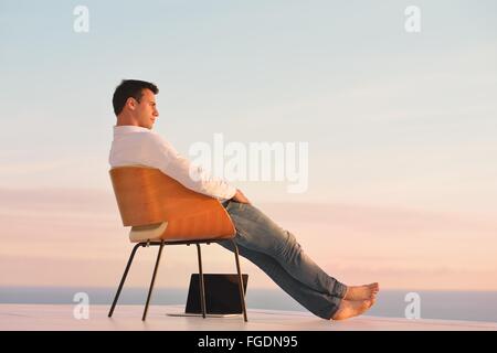relaxed young man at home on balcony Stock Photo