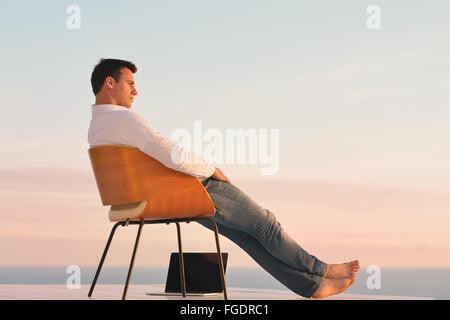 relaxed young man at home on balcony Stock Photo