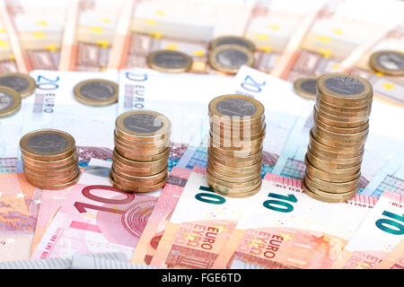 Stacks of coins increasing in size on a background of bank notes Stock Photo