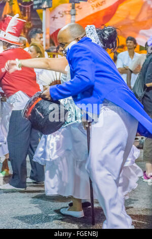 MONTEVIDEO, URUGUAY, JANUARY - 2016 - Costumed black man dancing candombe while marching at inagural parade of carnival of Monte Stock Photo