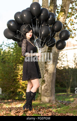 Young woman in black dress posing with black ballo Stock Photo