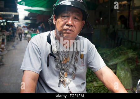 Man loaded down with good luck amulets in Bangkok Thailand. Amulets at the amulet marke, Bangkok, Thailand, Asia. Local religious amulets, charms, talismans & traditional medicines market. Stock Photo