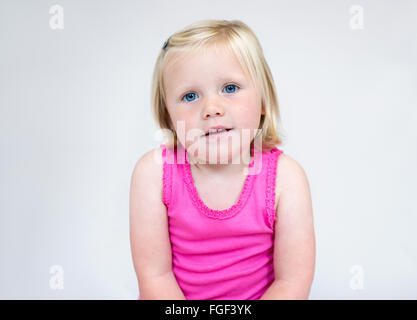 Portrait of a young girl with short blonde hair and blue eyes wearing a pink vest smiling Stock Photo