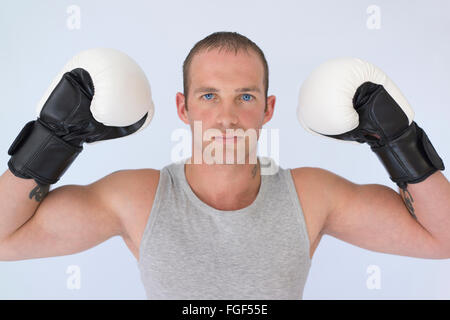 Man wearing boxing gloves flexing his biceps with a serious expression of concentration Stock Photo