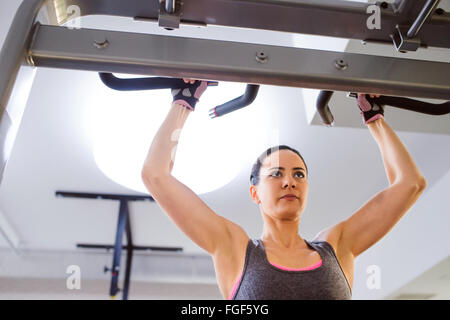 Woman in gym doing arms exercises on a machine Stock Photo