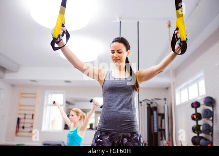Woman in gym training arms with trx fitness strips Stock Photo
